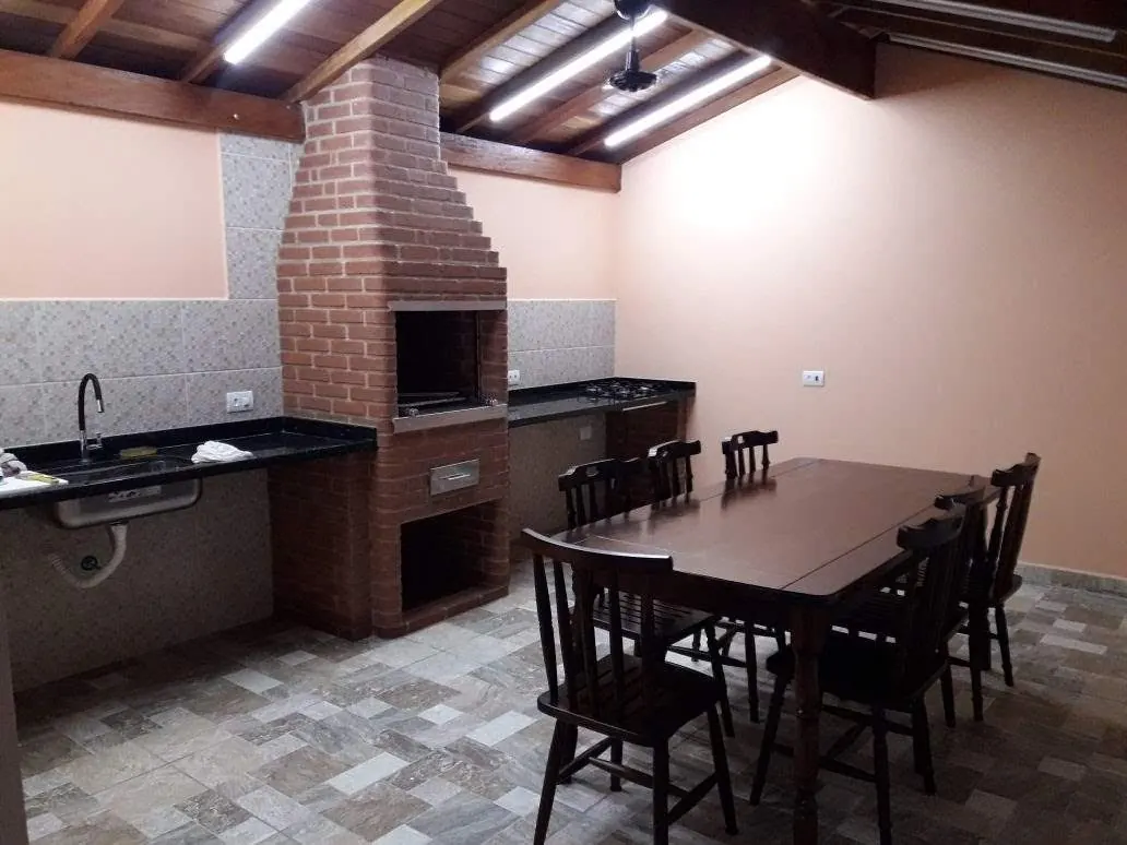 Área gourmet com churrasqueira de tijolo e mesa de jantar